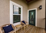 Thumbnail 67 of 94 - a porch with two chairs and a table and a green door