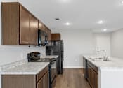 Thumbnail 4 of 58 - A kitchen with brown cabinets and black appliances.