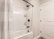 Thumbnail 35 of 57 - a bathroom with a shower and a tub and a shower curtain at swiftwater luxury apartments in port charlotte, fl