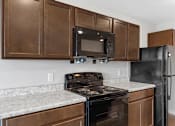 Thumbnail 6 of 58 - A kitchen with a black refrigerator, black stove, and black microwave.