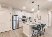Thumbnail 21 of 57 - an open kitchen with an island and stainless steel refrigerator at swiftwater luxury apartments in port charlotte, fl