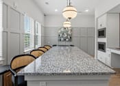 Thumbnail 37 of 51 - A kitchen with a granite countertop and chairs.