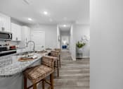 Thumbnail 29 of 51 - A kitchen with a counter and chairs.