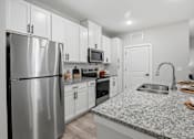 Thumbnail 15 of 51 - A kitchen with a stainless steel refrigerator, microwave, oven, and sink.