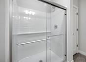 Thumbnail 16 of 51 - A white bathroom with a glass shower door.