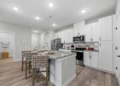Thumbnail 2 of 51 - A kitchen with white cabinets and a grey island.