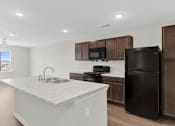 Thumbnail 11 of 58 - A kitchen with a black refrigerator and brown cabinets.