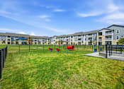 Thumbnail 8 of 45 - A playground area with a slide and swings in front of apartment buildings.