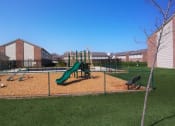 Thumbnail 6 of 14 - Playground with a slide and monkey bars inside a fenced area at Maple Tree Apartments in LaPorte, IN