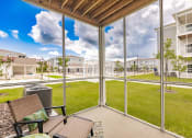 Thumbnail 40 of 57 - a screened enclosed patio with a table and chairs and screened at  a living room with tables and chairs and a ceiling fan at Swiftwater apartments in Port Charlotte, FL