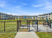 Thumbnail 13 of 45 - A playground with a slide and a fence in front of apartment buildings.