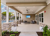 Thumbnail 7 of 94 - patio area with chairs, a table, and a tv at Vantage Luxury Apartments in  Cape Coral, FL