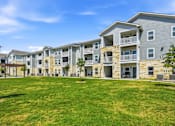 Thumbnail 4 of 45 - A large grassy area in front of apartment buildings.