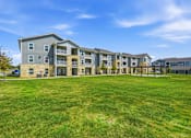 Thumbnail 3 of 45 - A large grassy area in front of apartment buildings.