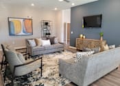 Thumbnail 14 of 31 - Clubhouse with empty couches and chairs with tv on the wall at Promenade Luxury apartments in Beaumont, Texas