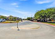 Thumbnail 22 of 45 - A roundabout with a sign on a pole in the middle of it.