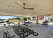 Thumbnail 21 of 45 - A patio with tables and chairs under a roof.