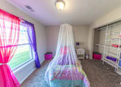 Thumbnail 16 of 43 - A room with a bed covered in a colorful bedspread and a canopy.
