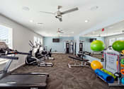 Thumbnail 20 of 45 - A fitness room with a treadmill, exercise balls, and other equipment.