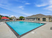 Thumbnail 33 of 45 - A large outdoor swimming pool with a red roofed building in the background.