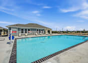 Thumbnail 32 of 45 - A large outdoor swimming pool with a building in the background.