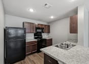 Thumbnail 23 of 45 - A kitchen with a black refrigerator, microwave, and stove.