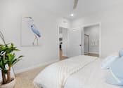 Thumbnail 34 of 83 - A bedroom with a bed, pillows, a ceiling fan, and a painting of a bird.