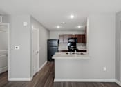 Thumbnail 27 of 45 - A kitchen with a black fridge and microwave, a white countertop, and brown cabinets.