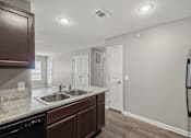Thumbnail 24 of 45 - A kitchen with a black fridge and brown cabinets.