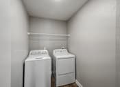Thumbnail 26 of 45 - Two white front loading washing machines in a small laundry room.