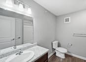 Thumbnail 40 of 45 - A white toilet sits in a bathroom with a marble countertop and a white sink.