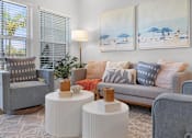Thumbnail 29 of 83 - A living room with a grey couch, two grey armchairs, a white side table, and two paintings on the wall.