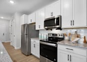 Thumbnail 38 of 83 - A kitchen with white cabinets and stainless steel appliances.