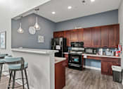 Thumbnail 11 of 34 - A kitchen with a bar area and a refrigerator.