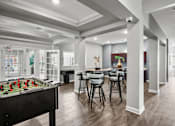 Thumbnail 9 of 34 - A foosball table is in the middle of a room with a dining table and chairs.