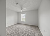 Thumbnail 27 of 34 - A room with a ceiling fan and carpeted floor.