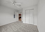 Thumbnail 26 of 34 - A room with a ceiling fan and a carpeted floor.