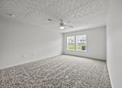 Thumbnail 22 of 34 - A room with a carpeted floor and a ceiling fan.