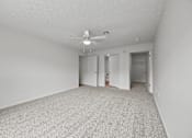 Thumbnail 25 of 34 - A spacious room with a ceiling fan and carpeted floor.