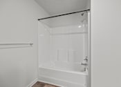 Thumbnail 28 of 34 - A white bathroom with a bathtub and a towel rack.