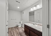 Thumbnail 30 of 34 - A bathroom with a toilet, sink, and mirror.