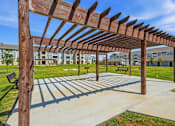 Thumbnail 12 of 45 - A wooden pergola structure is over a concrete walkway.