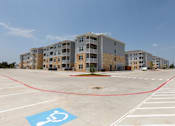 Thumbnail 36 of 39 - A parking lot with a handicap parking space in front of apartment buildings.
