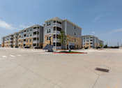 Thumbnail 35 of 39 - A large building complex with a parking lot in front.