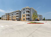 Thumbnail 38 of 39 - A large apartment complex with a parking lot in front.