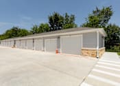 Thumbnail 34 of 39 - A long building with a grey roof and grey garage doors.