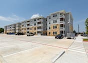 Thumbnail 39 of 39 - A parking lot in front of a multi-story apartment building.