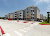 Thumbnail 31 of 39 - A large apartment complex with a parking lot in front.