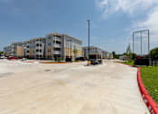 Thumbnail 32 of 39 - A parking lot in front of a multi-story apartment building.