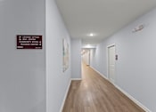 Thumbnail 6 of 39 - A long hallway with a sign on the wall pointing to the leasing office and mail center.
